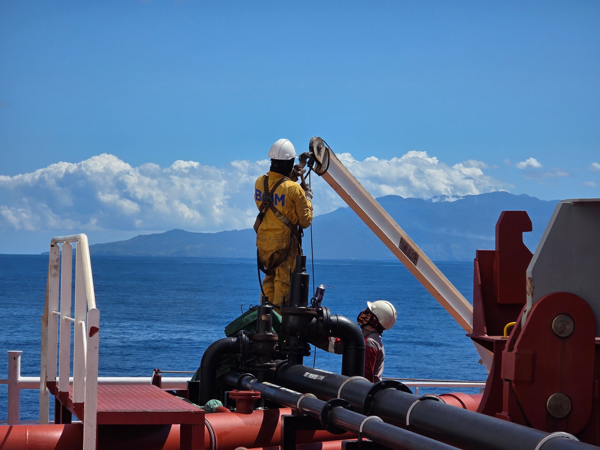 Workers in FR coveralls performing maintenance on an offshore oil platform